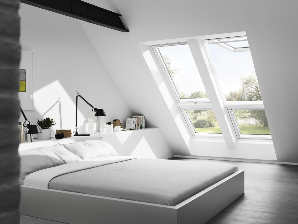 Schlafzimmer mit flachem Bett, zwei großen Dachfenstern und minimalistischem Interieur unter einer Schräge.